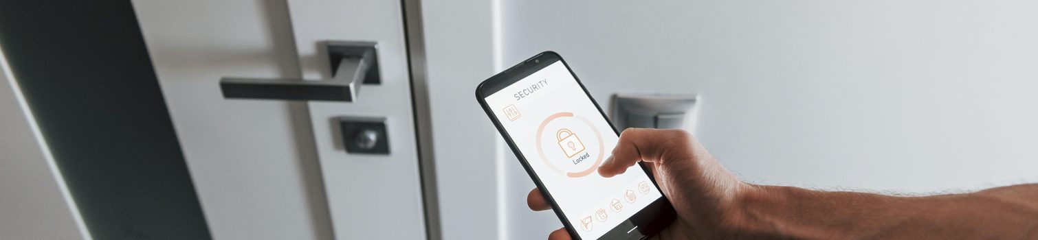 Cerraduras inteligentes: La comodidad conectada Con el móvil en la mano abre una puerta con cerradura inteligente.