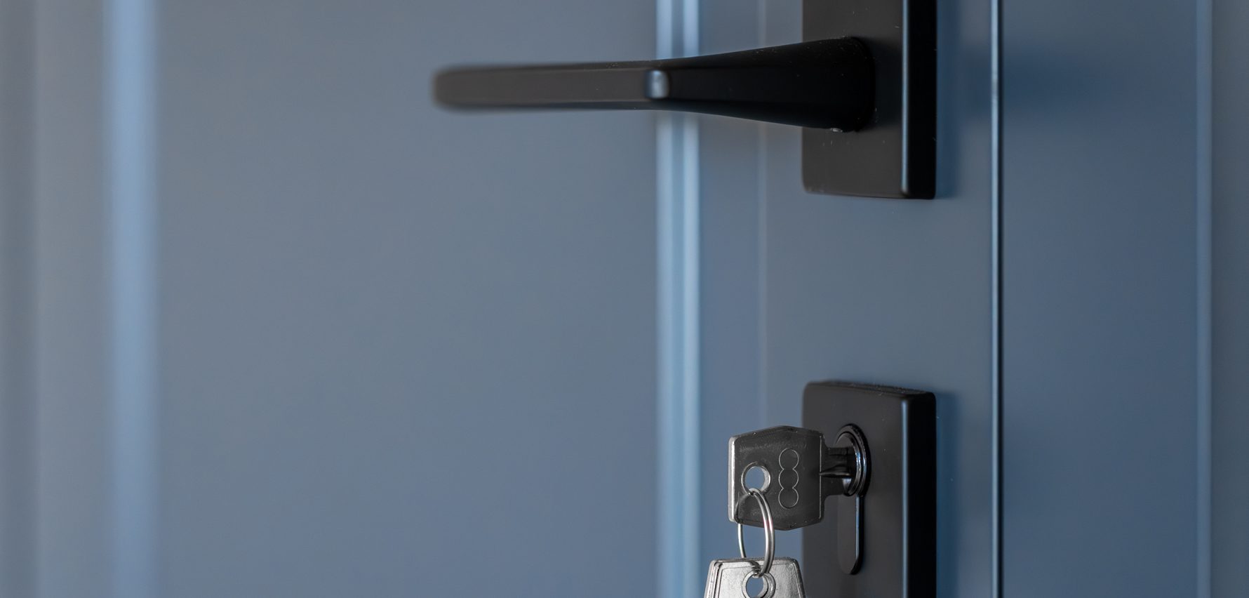 Vista parcial de una puerta, su picaporte, la cerradura y una llaves.