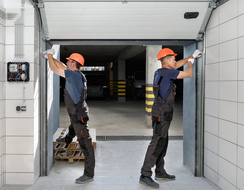 automatismos servicios I Dos operarios de keys cerrajeros instalan una puerta automática de un garaje.