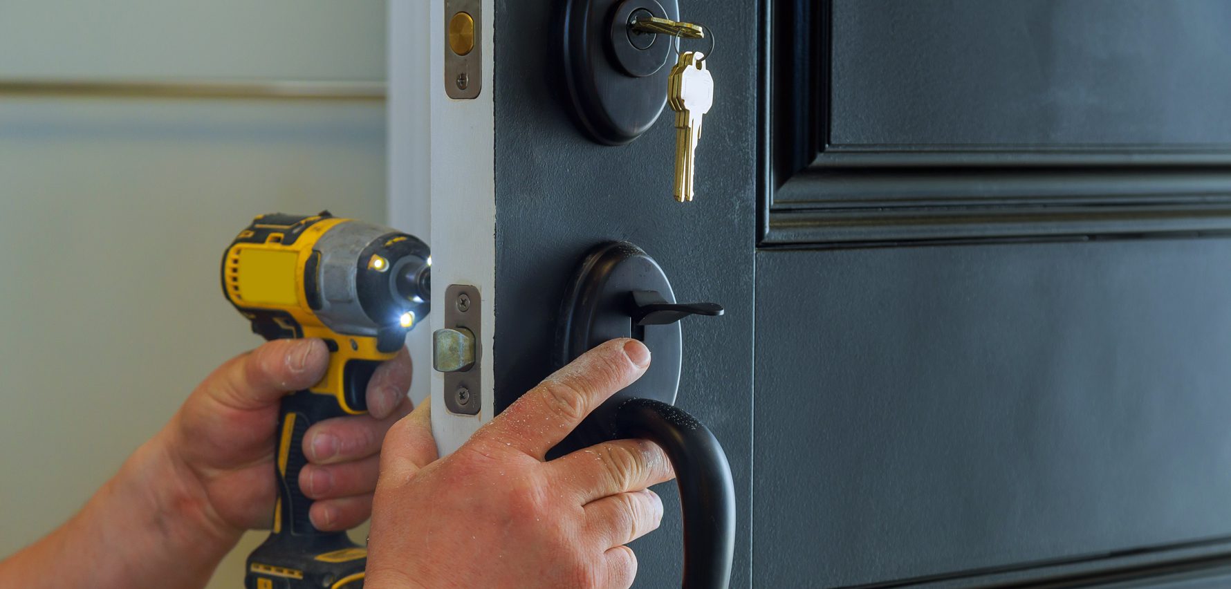 Primer plano de las manos de un cerrajero de urgencia instalando una cerradura en la puerta.