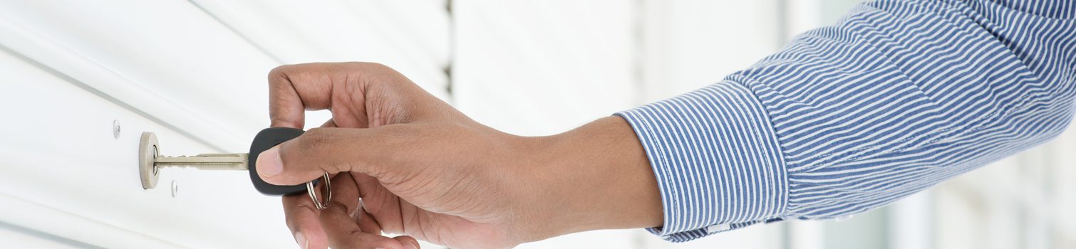 insights cerrajero negocio interior uno Primer plano de una mano con una llave abriendo el cierre metálico de un negocio.